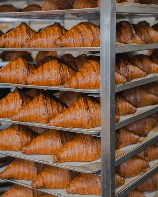 Bandejas de croissants recién horneados en los carros del obrador de Forn de Barri