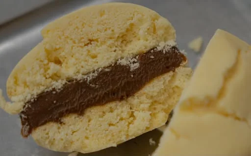 Alfajor abierto relleno de dulce de leche junto a un trozo de mantequilla
